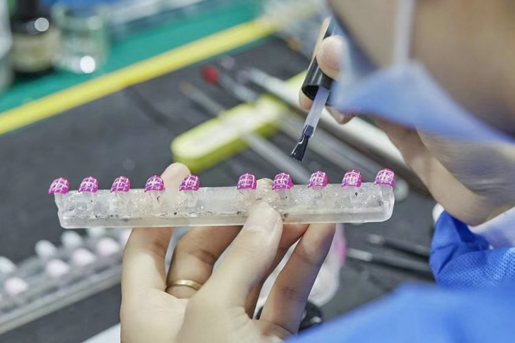 Lavara technician hand-painting intricate glitter designs on custom pink press-on nails.
